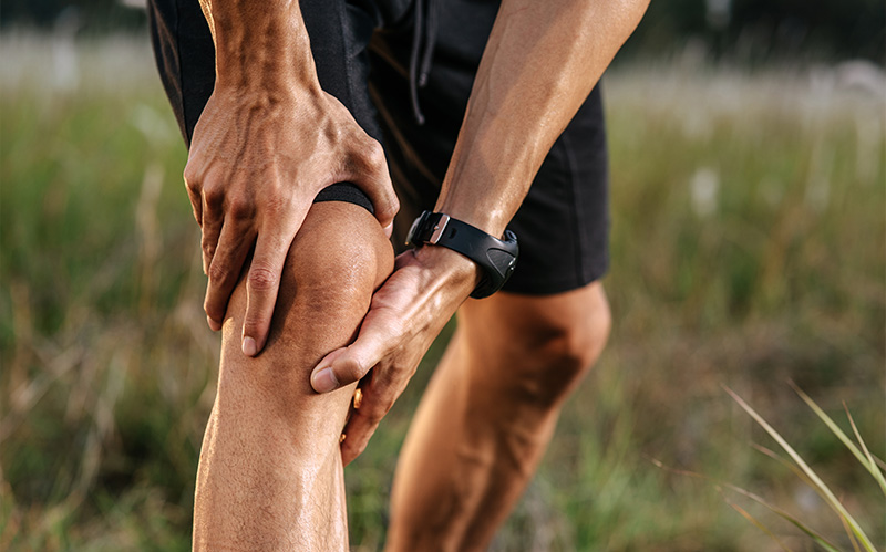 An athlete clutching their knee in pain during an outdoor workout