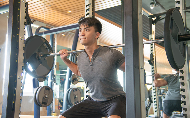 Athlete performing barbell squats requiring healthy rotator cuff joints.