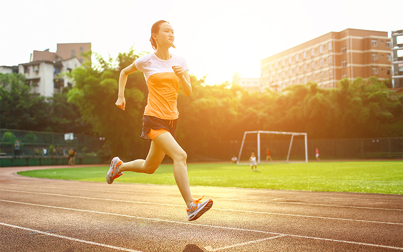 Female runner jogging on track experiencing deep buttock pain.