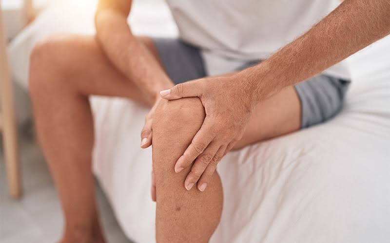 Person clutching a painful knee, illustrating a sudden lock or catch.