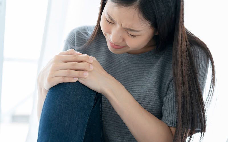 Woman clutching her knee in pain from a sports injury.